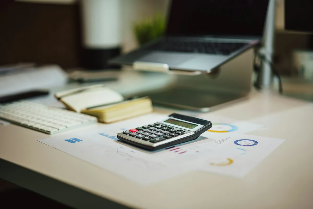 Calculator resting on tax documents and financial paperwork on a desk
