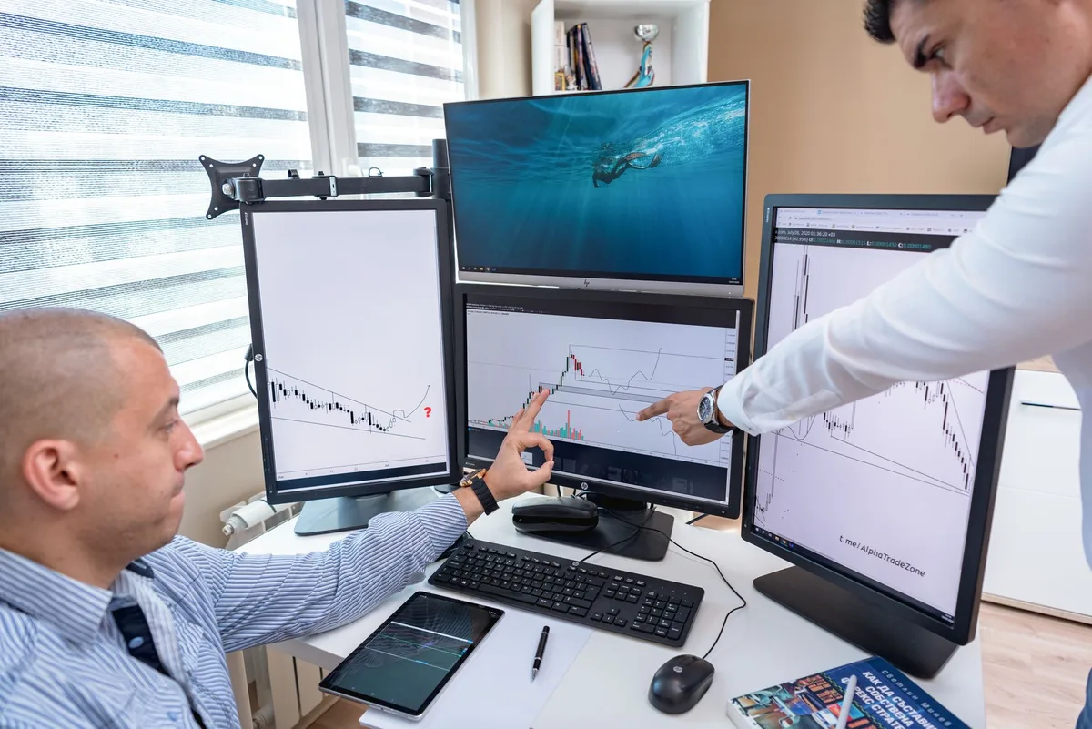 Financial data charts displayed on multiple computer screens showing market analysis