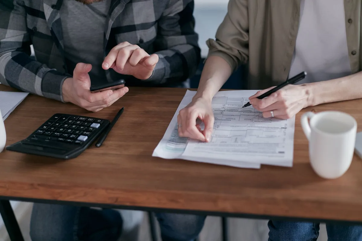 Calculator resting on tax documents and forms on a wooden desk