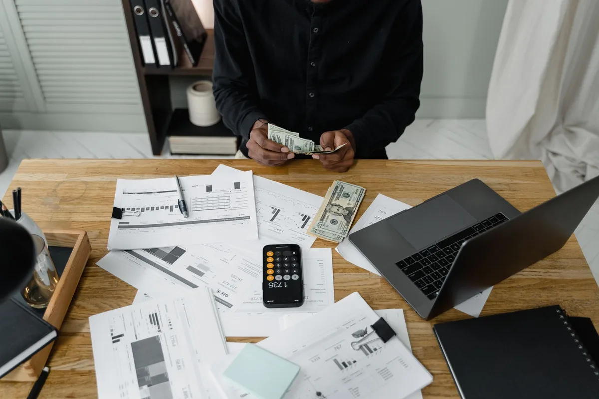 Calculator with coins and financial documents on a wooden desk representing GIC calculations