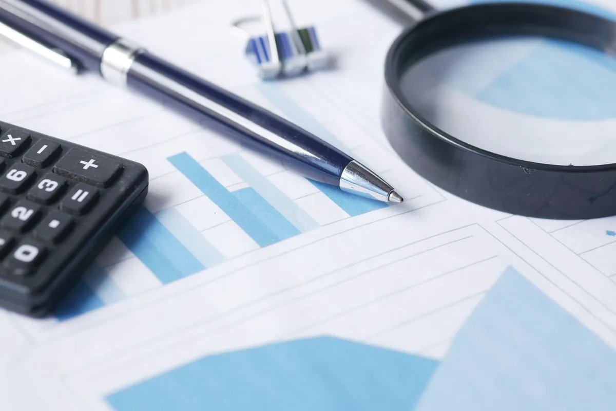 Calculator resting on financial documents with a pen, representing tax planning and registered account decisions