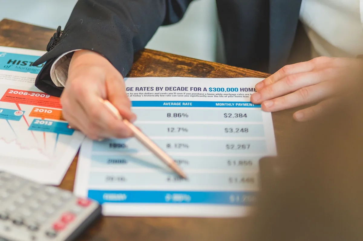 Financial planning workspace with documents, calculator, and pen on a wooden desk