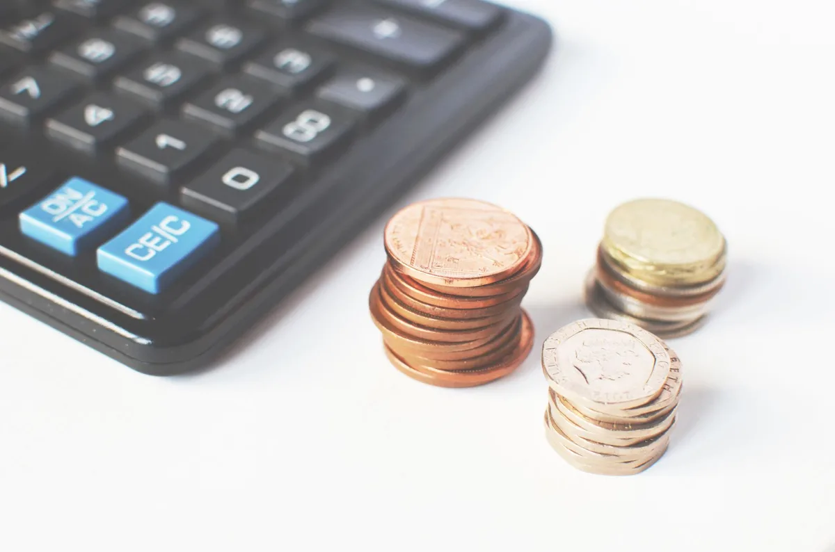 Calculator and stacked coins on a desk representing savings calculations
