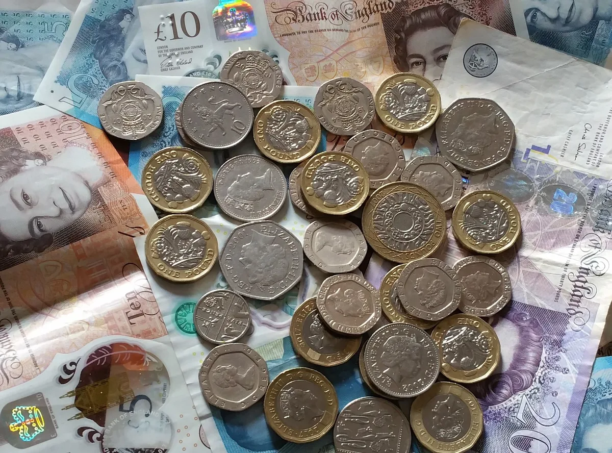 Calculator and British pound coins on a desk showing savings calculation