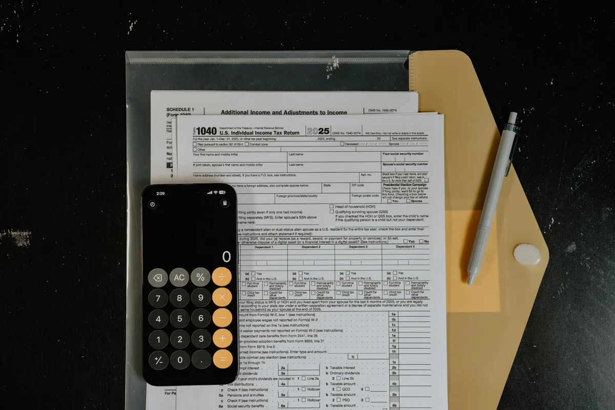 Calculator resting on financial documents with pen, representing tax planning and investment calculations