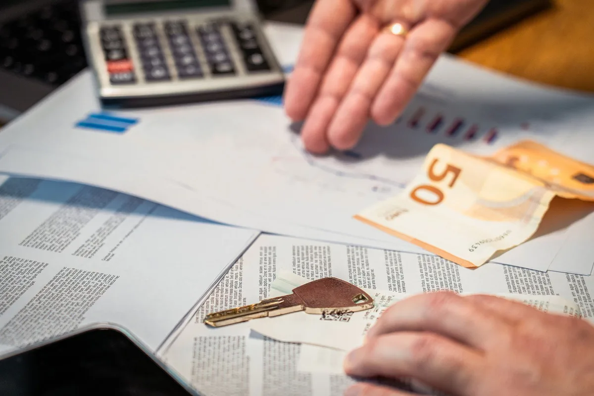 Notas de real brasileiro com calculadora e documentos de investimento sobre mesa