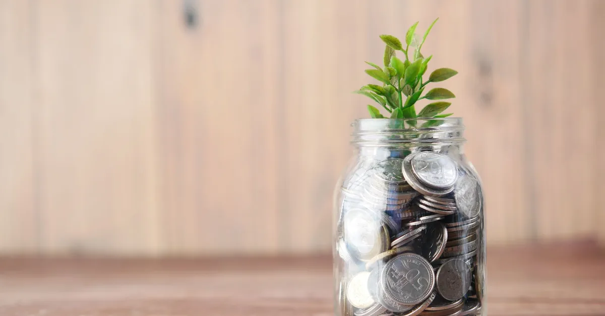 Cofrinho azul cercado por moedas douradas representando economia e reserva financeira