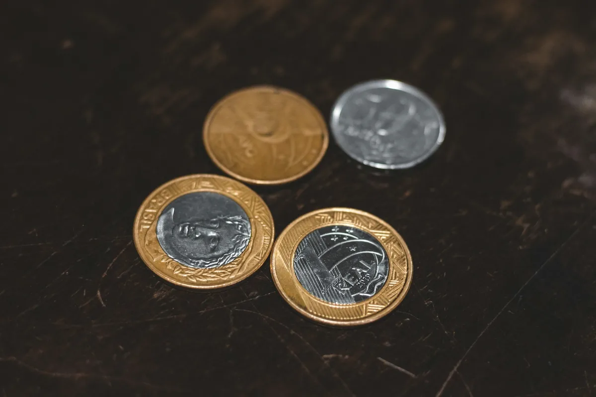 Calculadora ao lado de moedas sobre uma mesa, simbolizando planejamento financeiro e quitação de dívidas