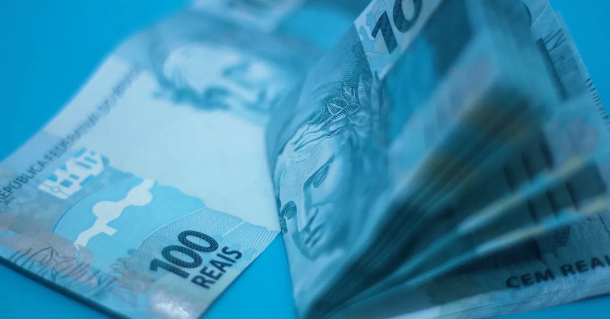 Jornal sobre economia ao lado de óculos e anotações financeiras