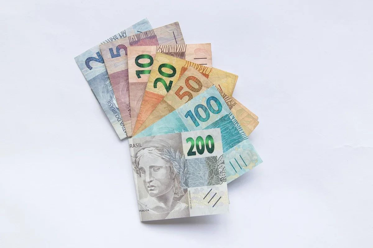 Notas de dinheiro brasileiro representando o impacto da inflação no poder de compra ao longo do tempo