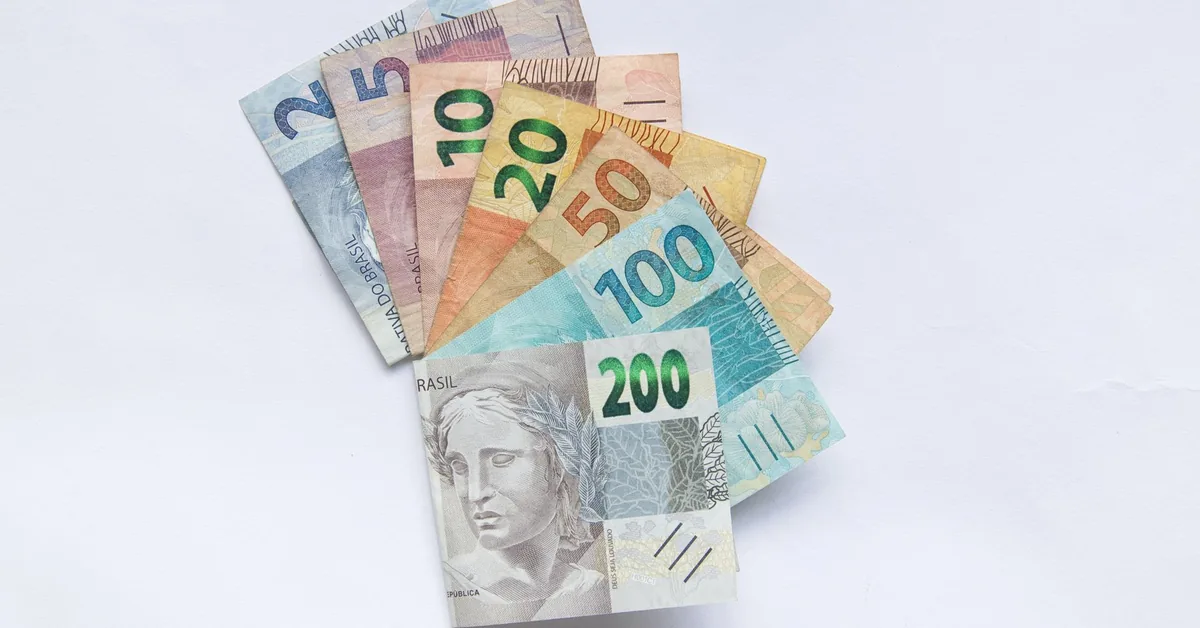 Calculadora, moedas e anotações usadas para simular rendimento de investimentos