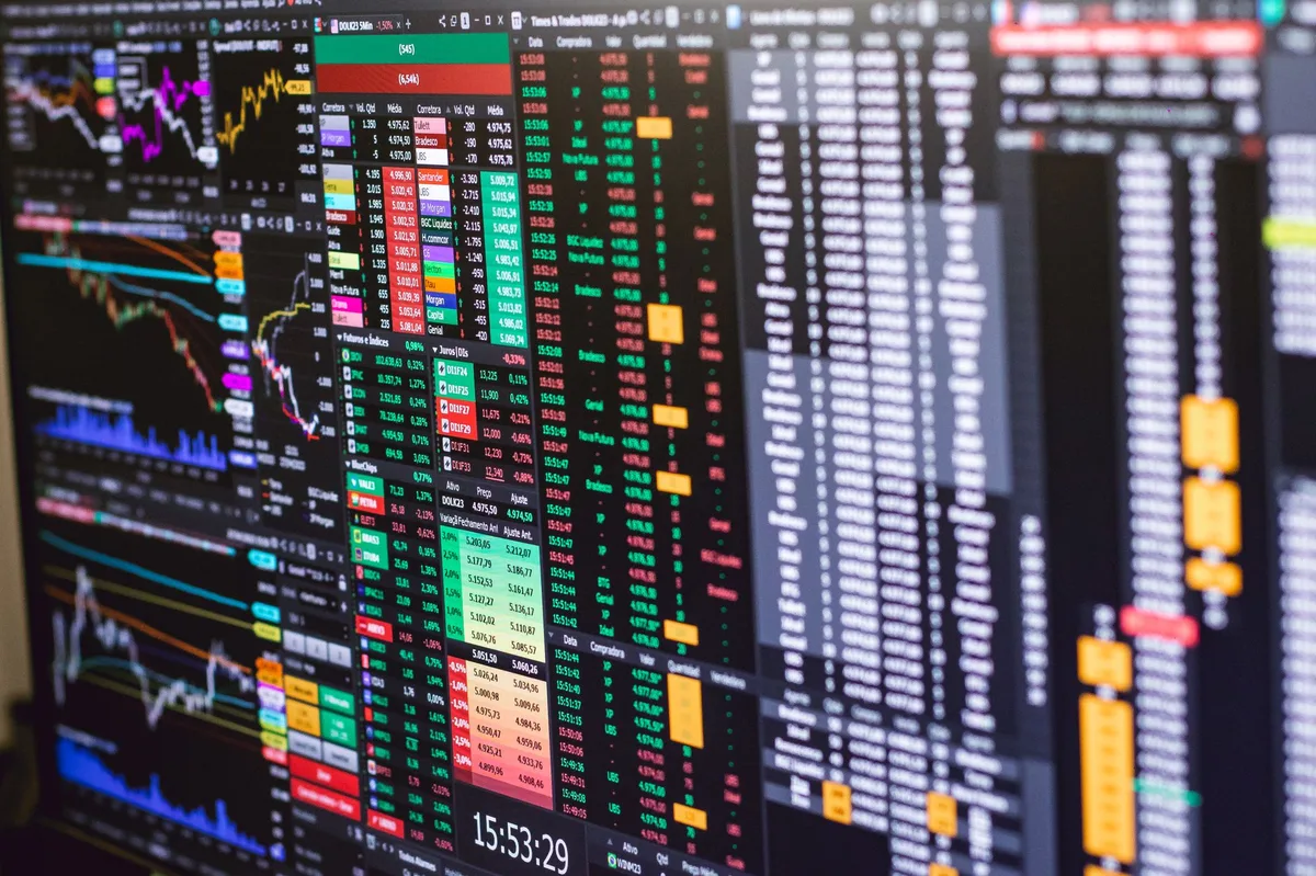 Gráficos de linhas financeiras coloridas exibidos em uma tela digital, mostrando oscilações do mercado de ações e renda fixa
